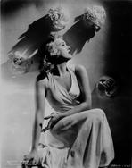 Betty Grable - Betty Grable Seated Heads Up Looking to the Left with Hand Rested on the Lap in White Halter Dress